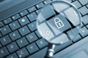 Vue rapprochée à travers une loupe d'une touche de clavier d'ordinateur affichant une icône de cadenas blanc, symbolisant la cybersécurité et la protection des données.